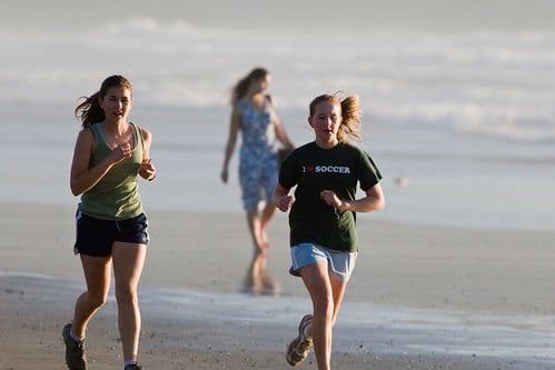 Two female girls jogging on the sand beach in late evening light