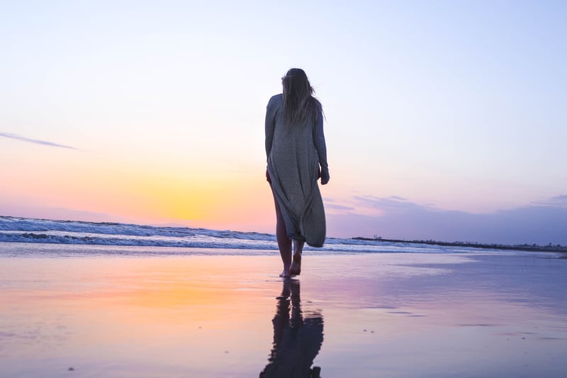 女性獨自走在沙灘如夢中。