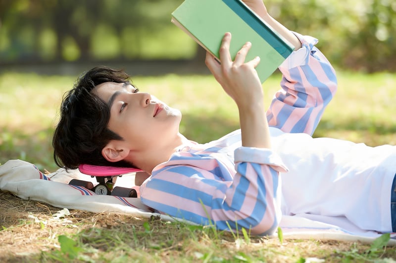 男性躺在草地上看書。