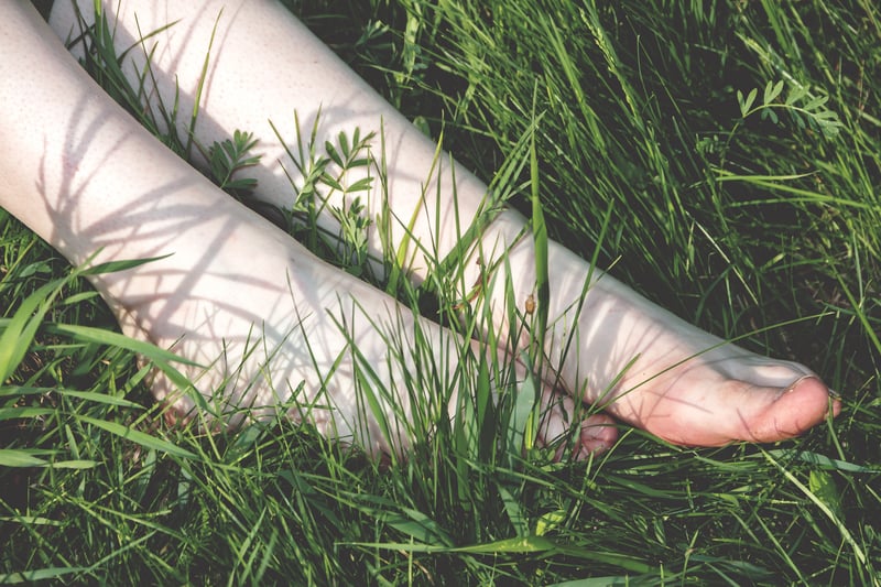 女性赤腳走在草地上。